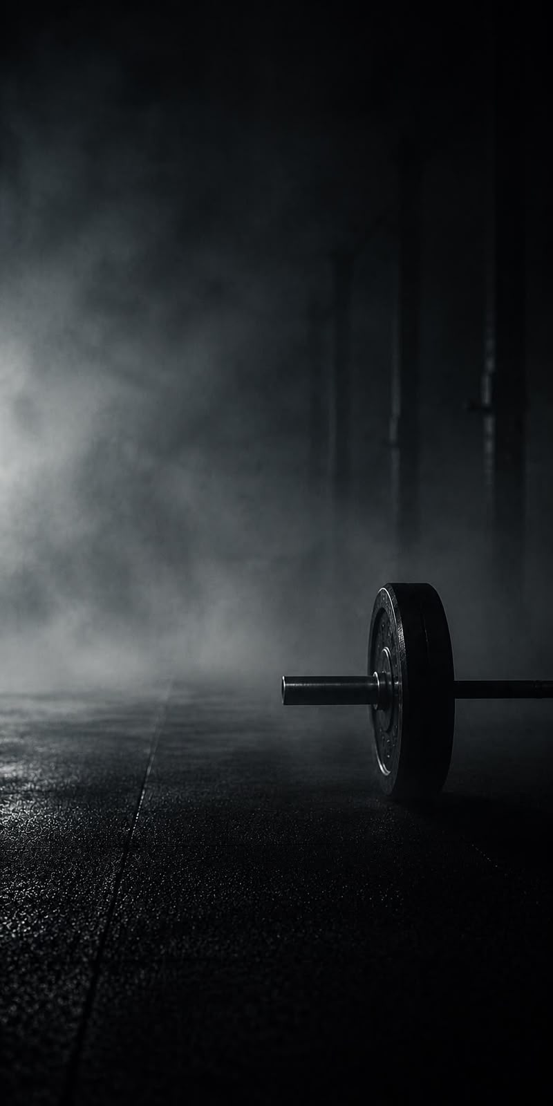 Barra de pesas sobre el piso de un gimnasio en penumbra
