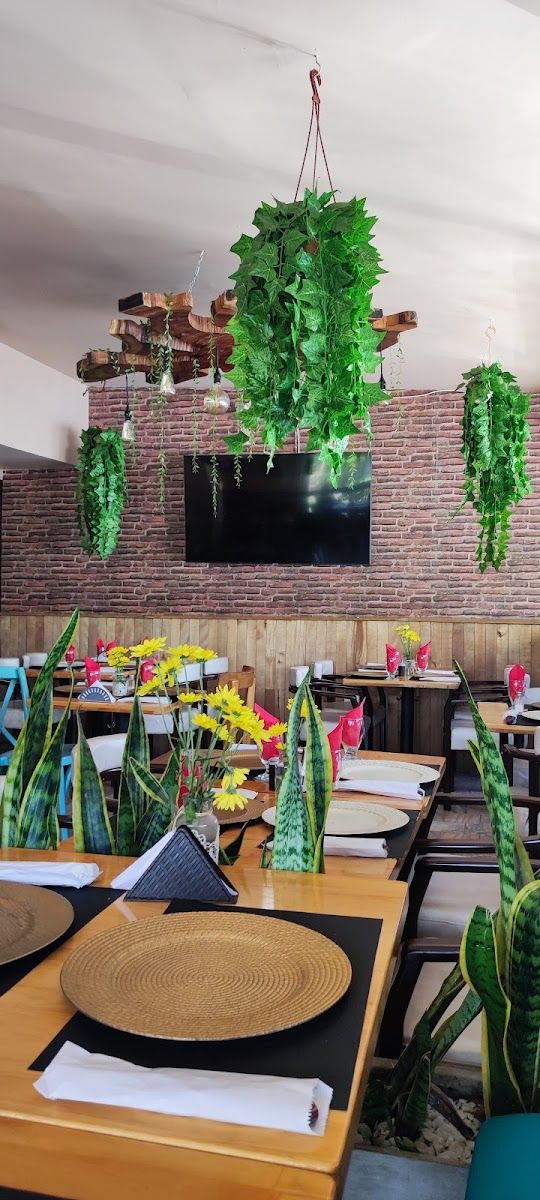 Salón con plantas colgantes — Charrua’s Parrilla