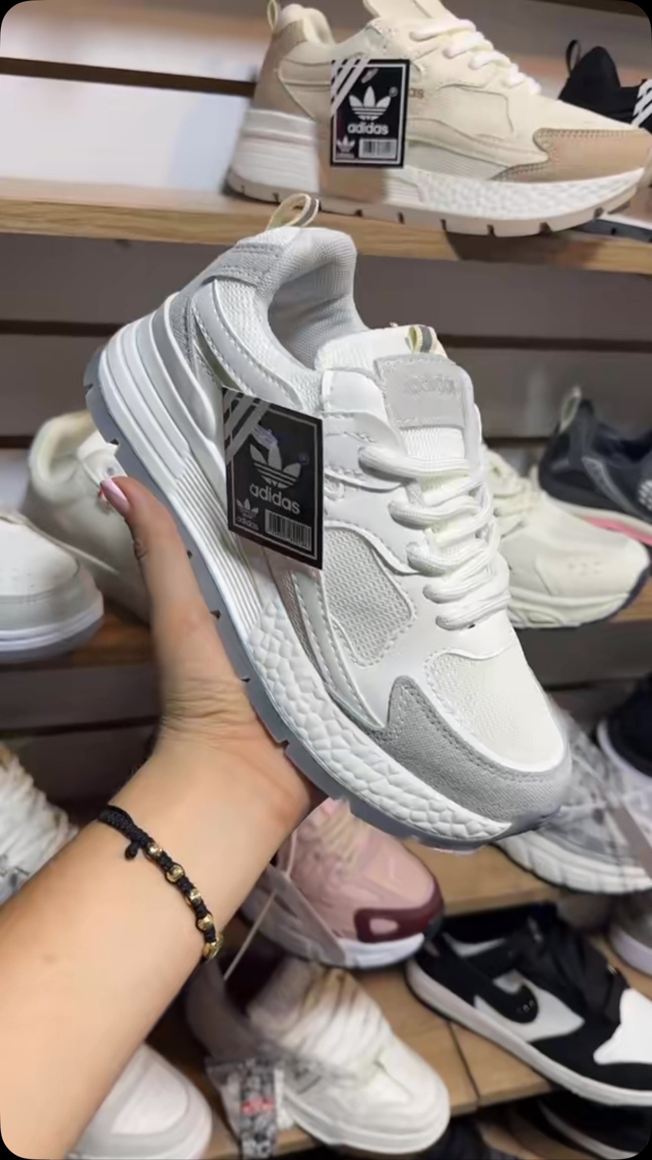 Tenis Adidas en la mano, frente a la vitrina de K&N Footwear