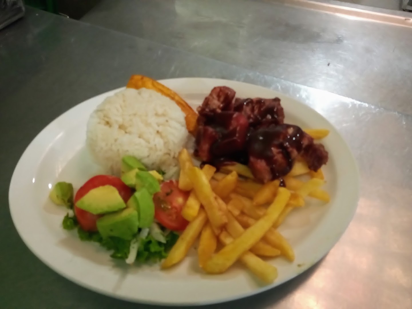 Plato con carne en salsa, arroz, papas y ensalada