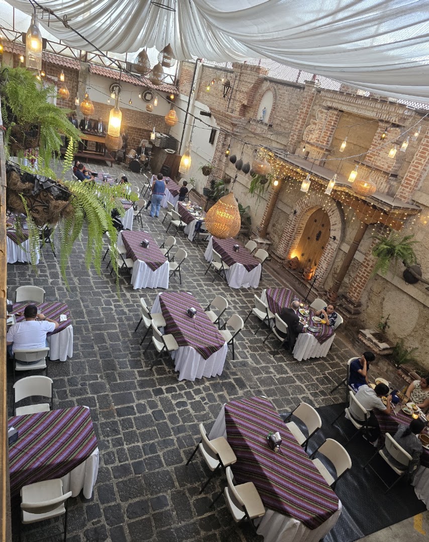 Patio con mesas y arcos de piedra — Restaurante El Adobe • Zona 1