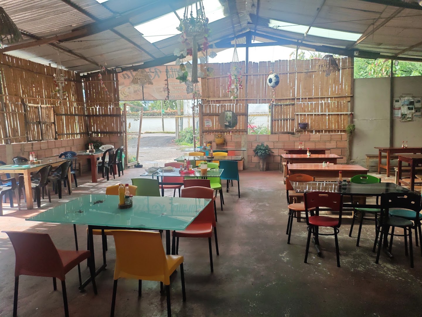 Comedor rústico con techo de guadua y sillas de colores